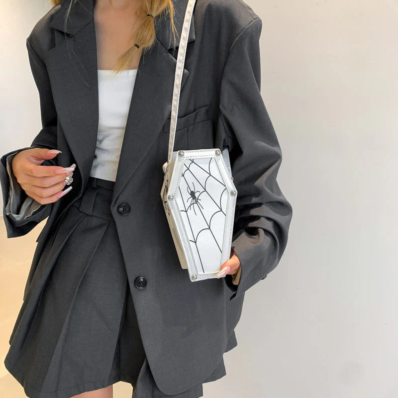 White spider-web coffin purse worn with a dark jacket