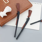 Brown-and-black rifle-shaped pen beside an open notebook