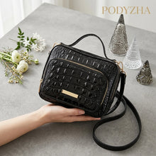 Black crocodile-embossed structured satchel with top handles and gold-tone hardware